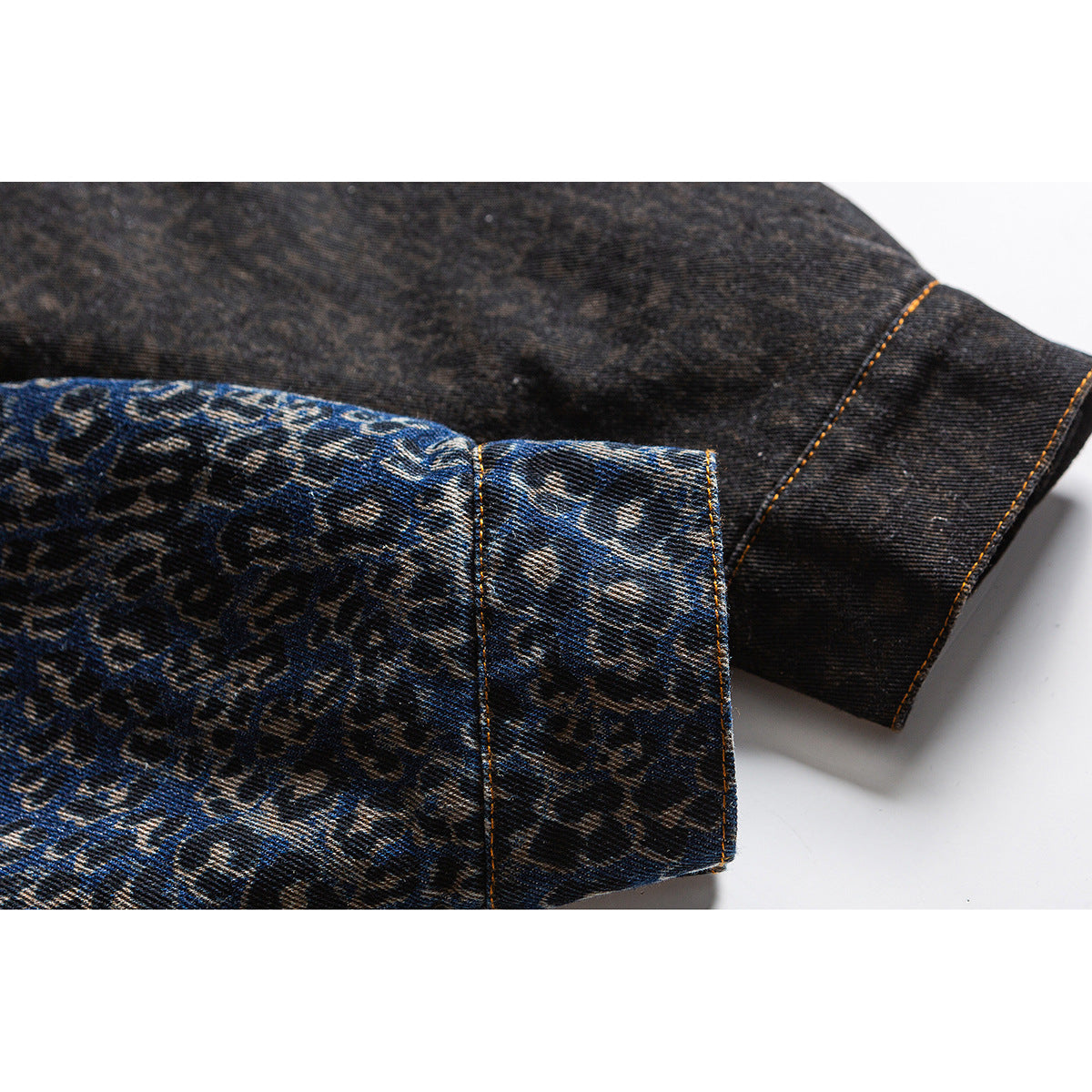 Close-up of the leopard-print denim jacket sleeve cuff with contrasting dark reverse fabric and orange stitching.
