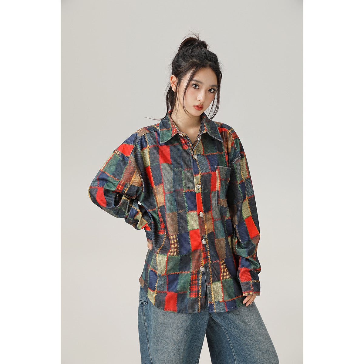 Model wearing an oversized multicolor patchwork plaid button-up shirt with a chest pocket and wide-leg jeans, front view.