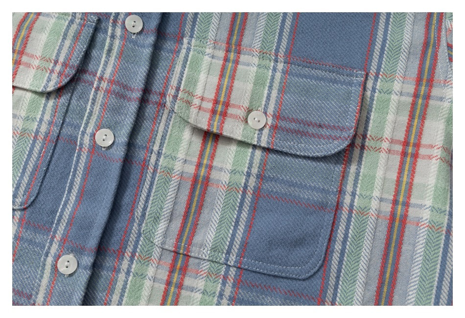 Close-up of a blue plaid shirt front with white buttons and a flap chest pocket.