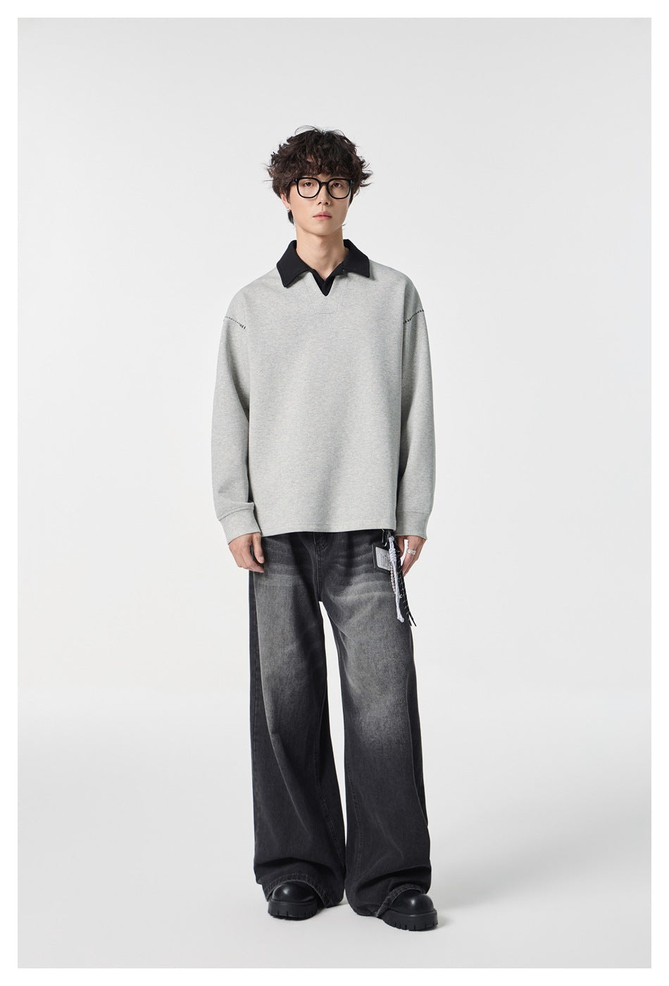 Model wearing a light gray pullover with a black collar and subtle stitched shoulder details.