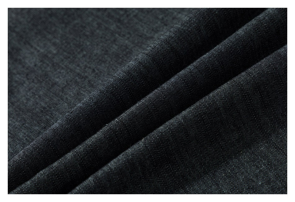 Close-up of dark denim fabric folded to show its woven texture.