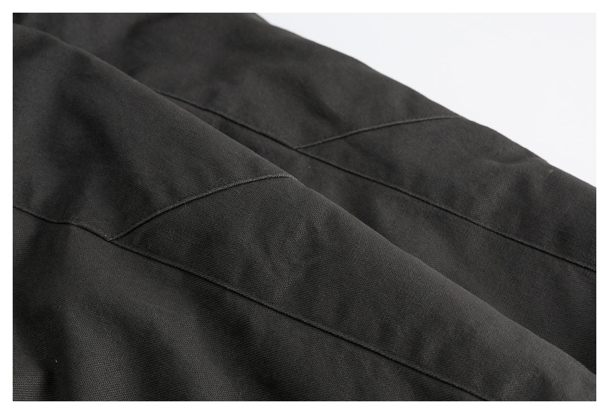 Close-up of dark charcoal garment fabric with diagonal stitched panel seams.