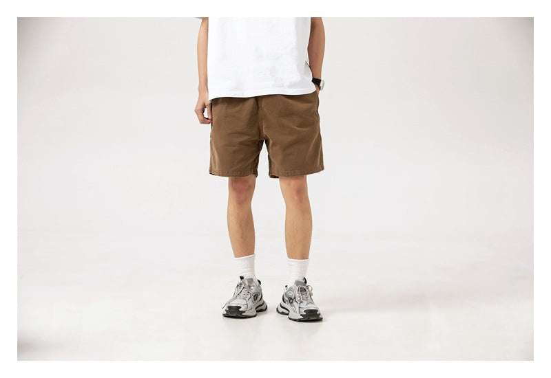 Front view of a person wearing plain brown shorts and a white T-shirt.