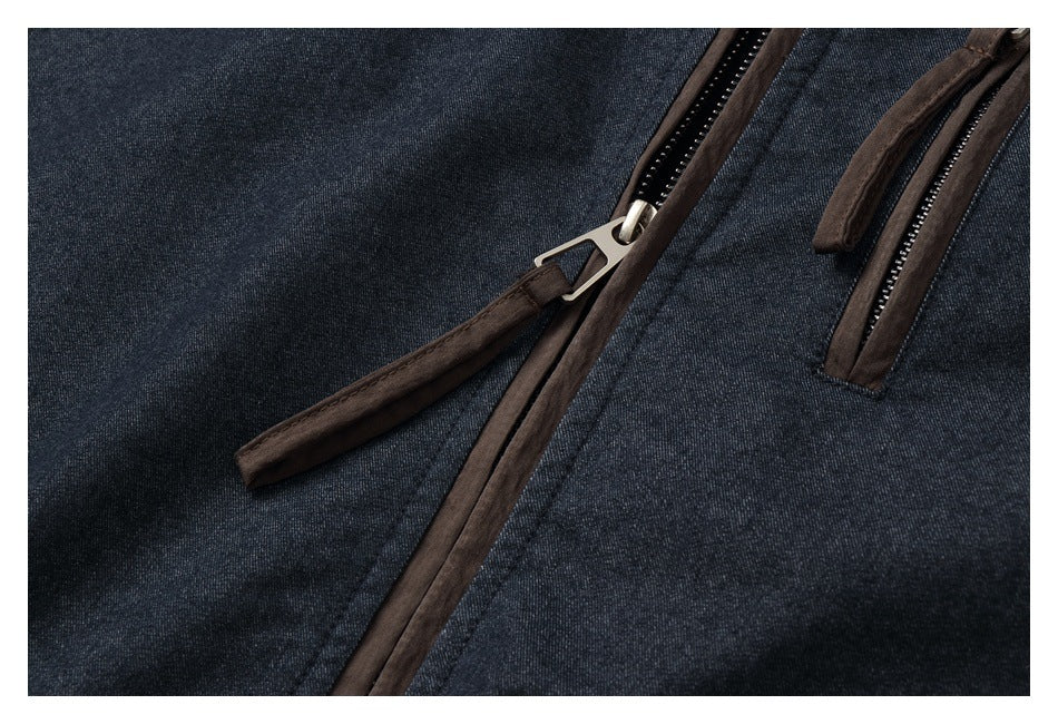 Close-up of a dark charcoal jacket with brown-trimmed zippers and a metal zipper pull.