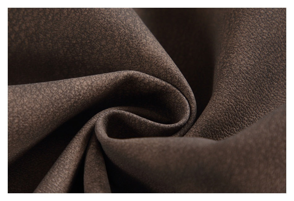 Close-up of softly folded brown fabric showing a fine mottled surface texture.