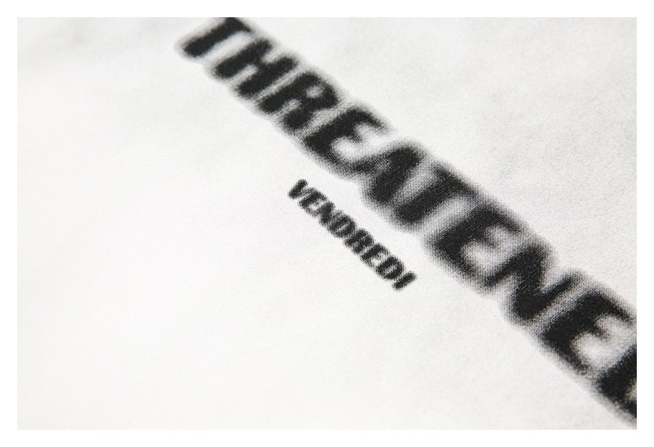 Angled close-up of black printed lettering and smaller text on white T-shirt fabric.