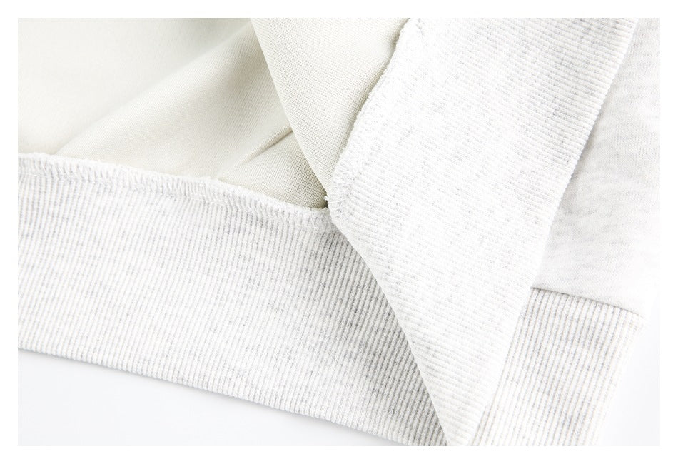 Close-up of an off-white garment seam and wide ribbed band.