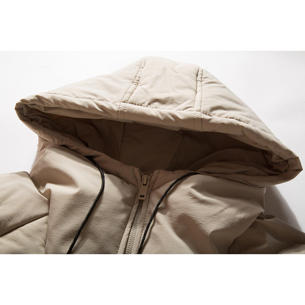 Close-up of a beige hooded jacket showing the hood, drawstrings, and front zipper.