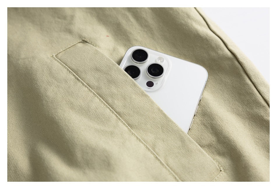 A white phone tucked into a slanted pocket on beige garment fabric.
