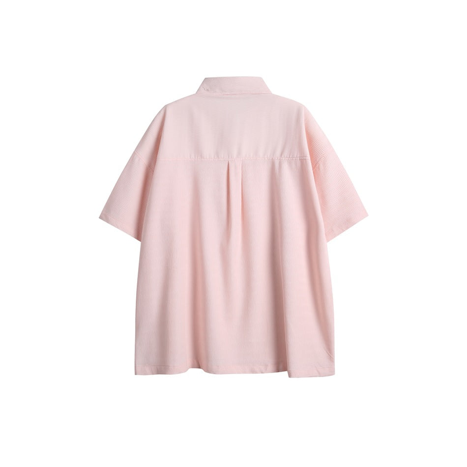 Back view of a pale pink short-sleeve collared shirt with a yoke seam and center pleat.