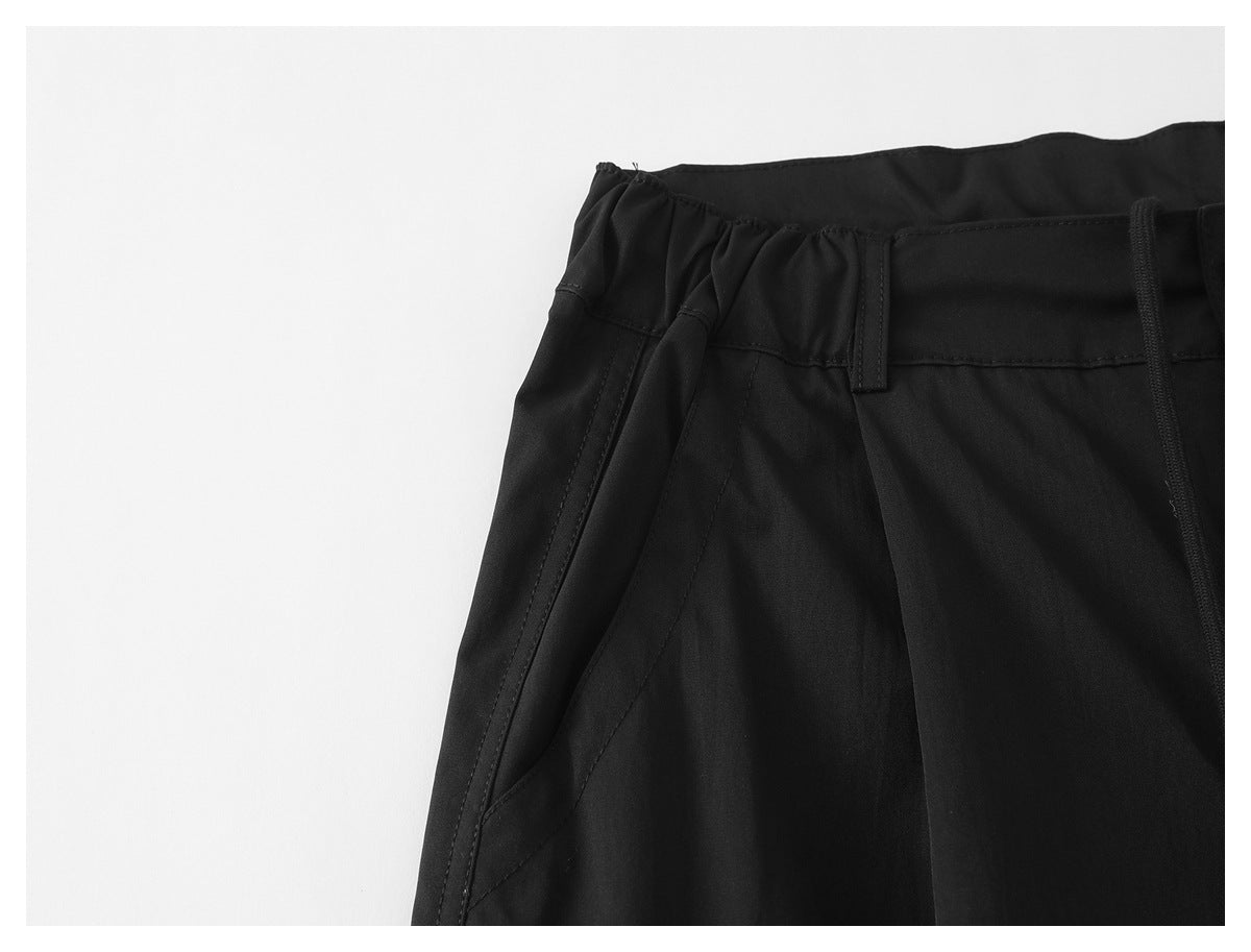 Close-up of black pants showing a slanted front pocket and gathered waistband.