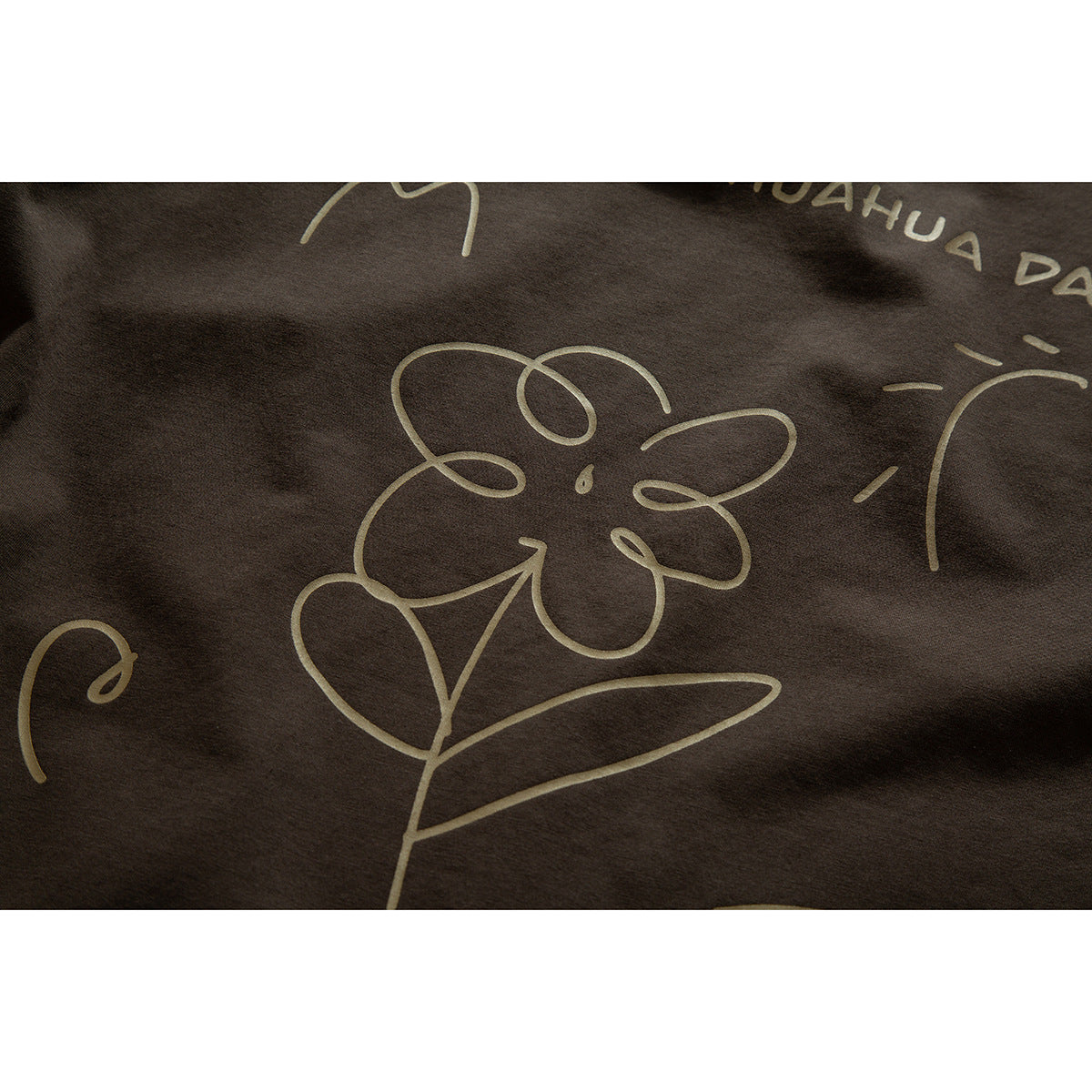 Close-up of a dark brown T-shirt with a pale line-drawn flower and lettering.