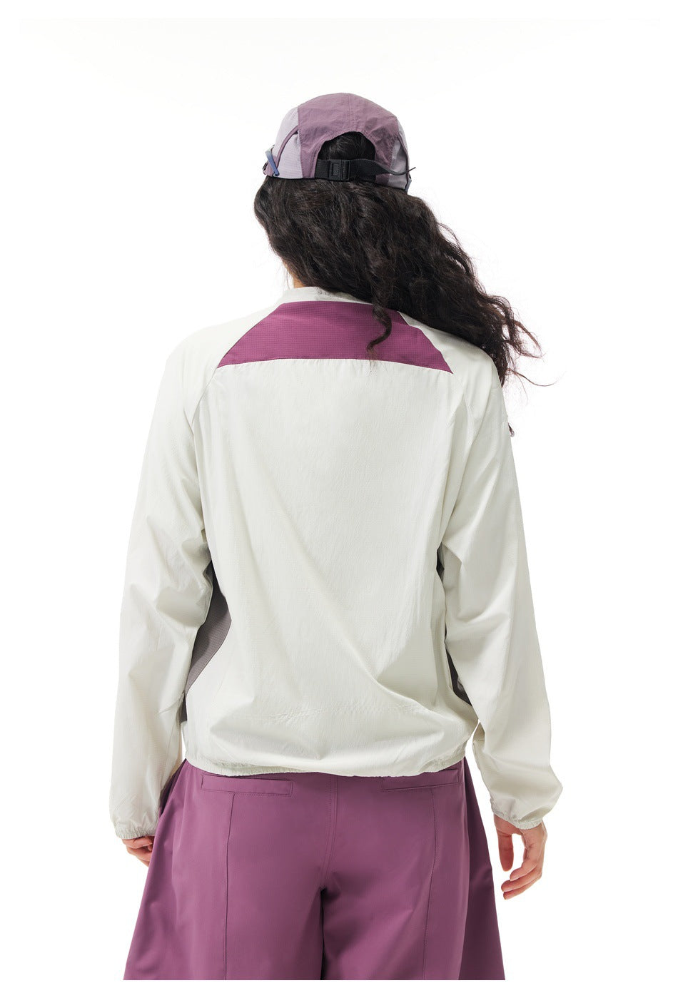 Back view of a model wearing an off-white jacket with a plum shoulder panel and plum pants.