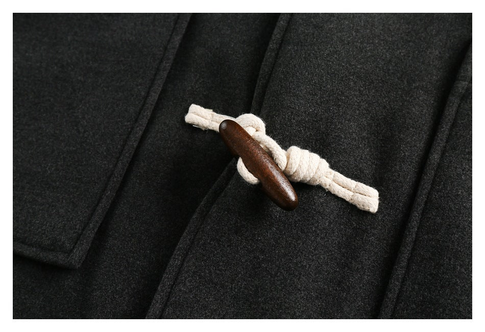Close-up of a cream rope loop and dark wooden toggle fastening on the charcoal coat.
