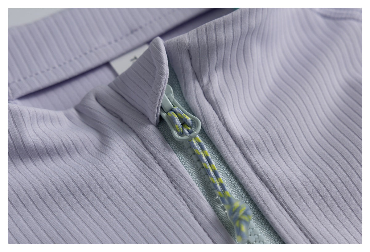 Close-up of a lavender ribbed garment’s front zipper and patterned cord pull.