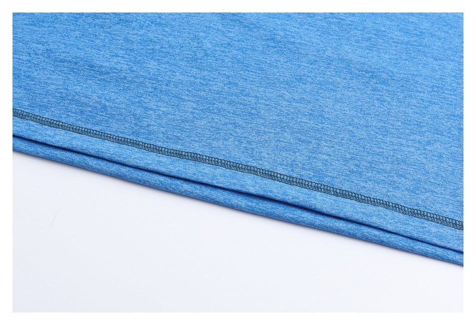Close-up of blue heathered fabric showing a dark overlock stitch along the folded hem.
