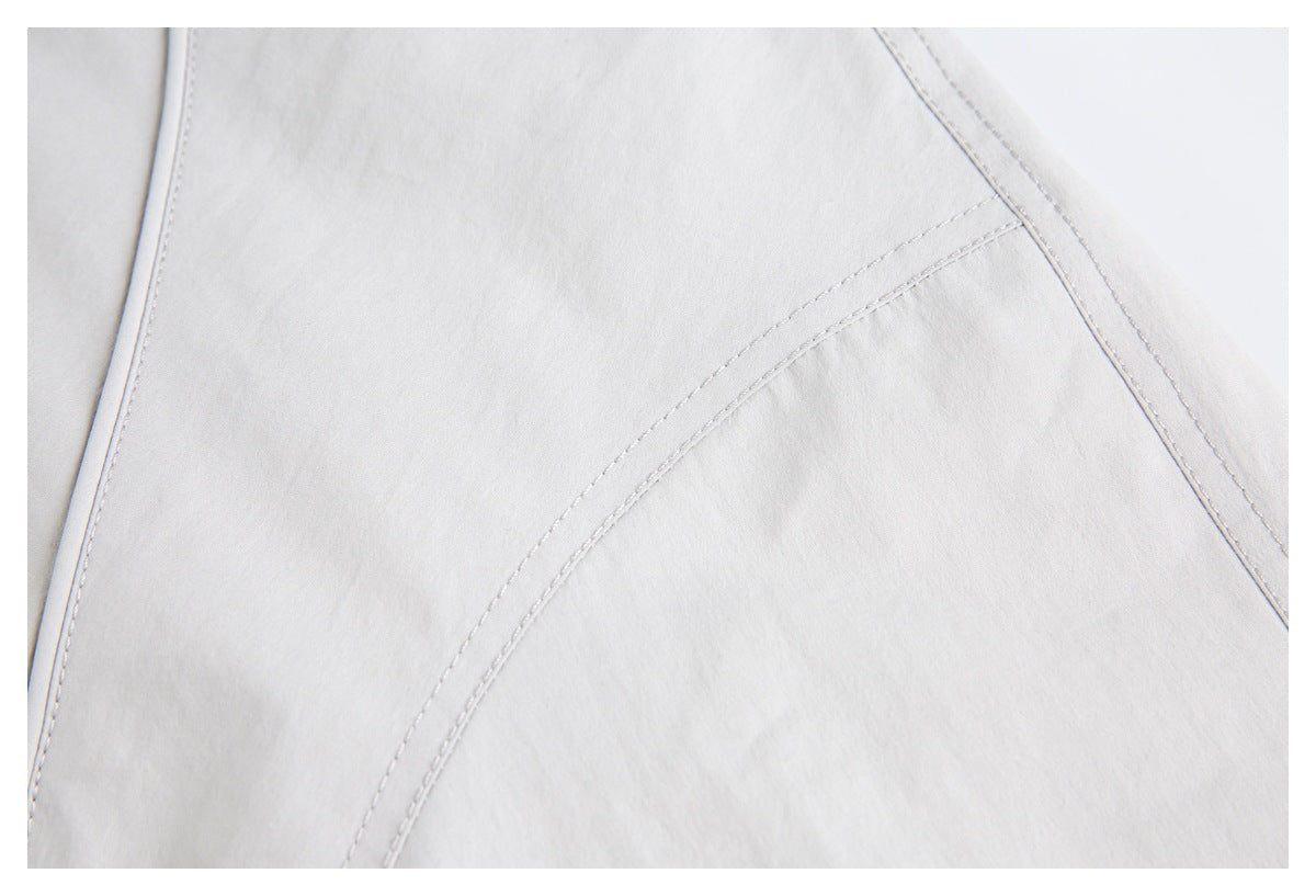 Close-up of curved stitched seam panels on the light gray jacket.