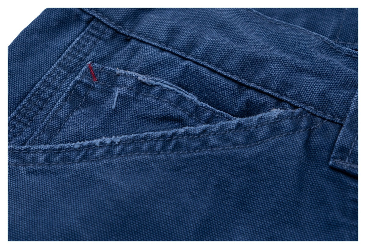 Close-up of dark blue trousers showing a pocket opening, seam stitching and a belt loop.