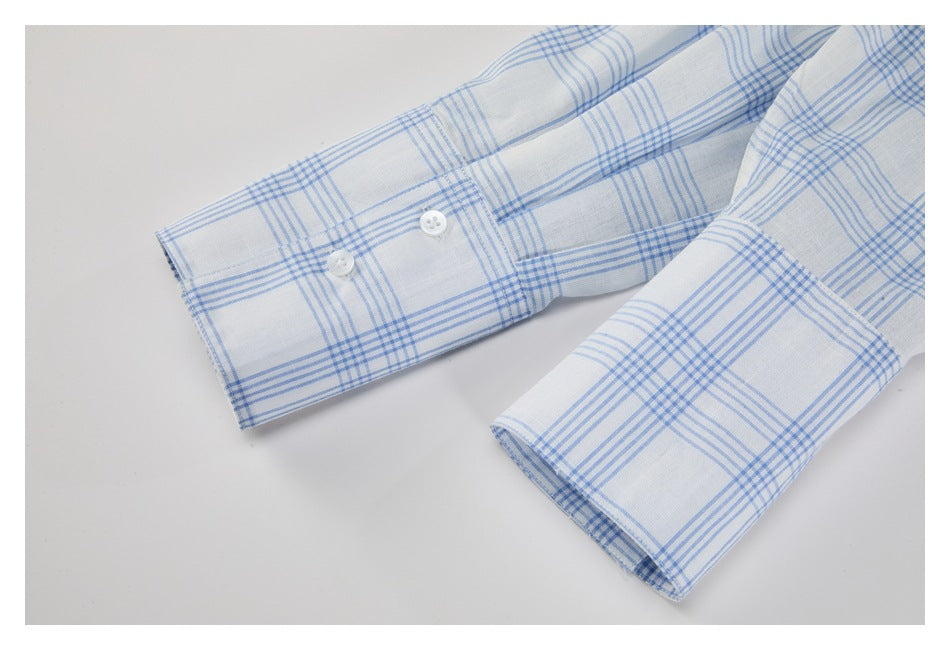 Close-up of two white shirt cuffs with buttons and a light blue plaid pattern.