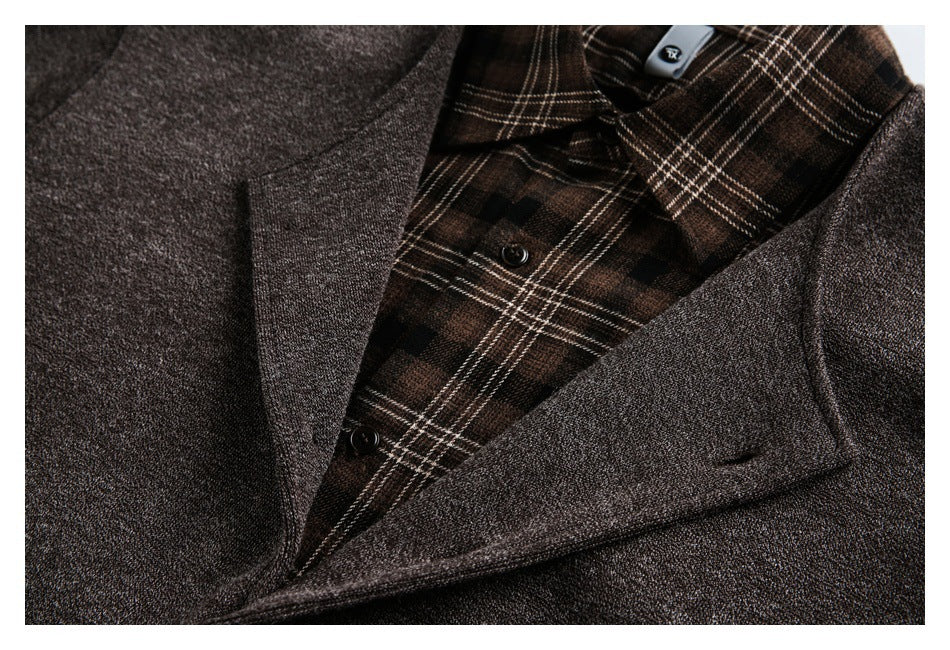 Close-up of a brown jacket lapel over a brown plaid inner layer with dark buttons.