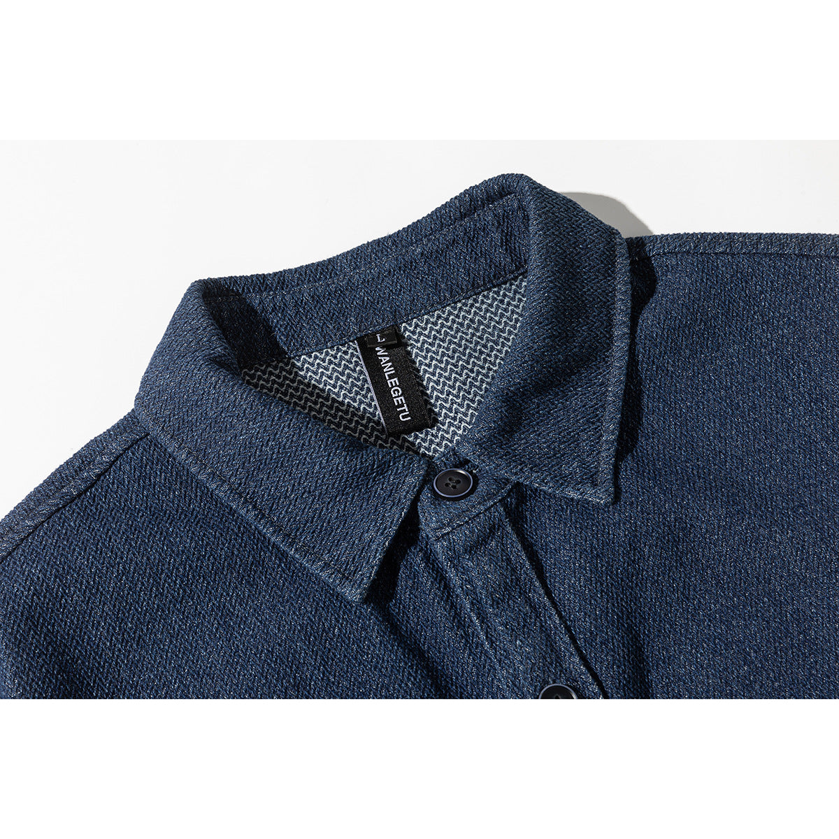 Close-up of a dark blue shirt collar, button placket, patterned inner yoke, and black neck label.