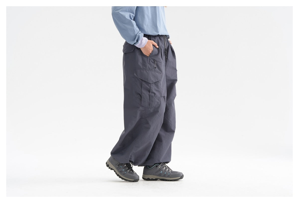 Cropped side view of a model wearing dark slate wide-leg cargo pants with flap pockets and hiking shoes.