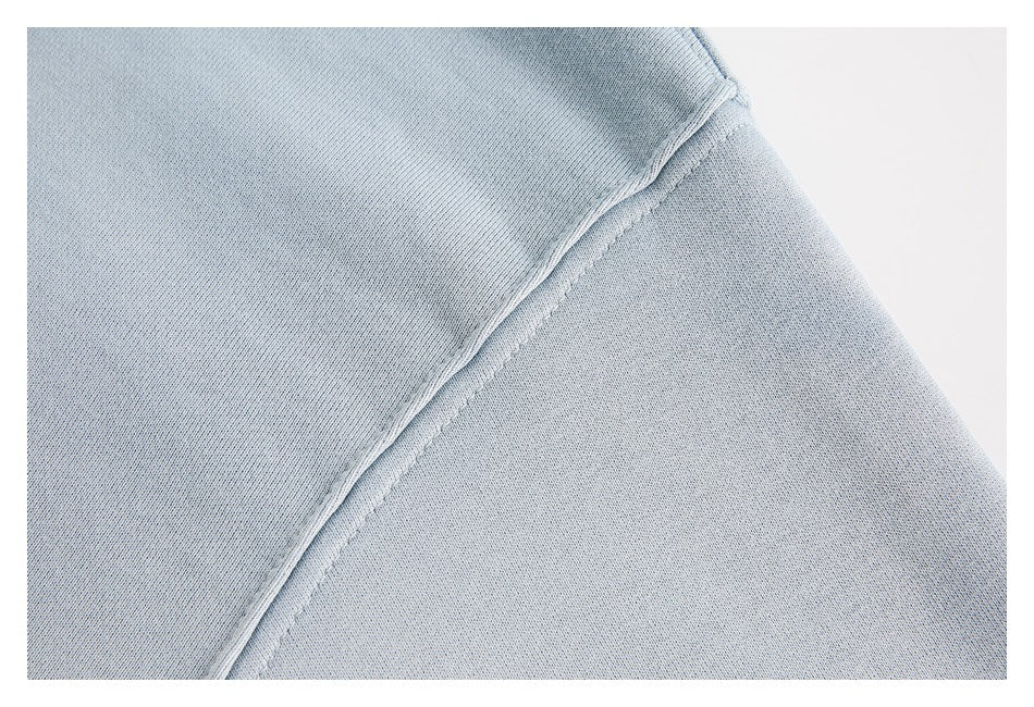 Close-up of the light blue sweatshirt’s sleeve seam and stitching.