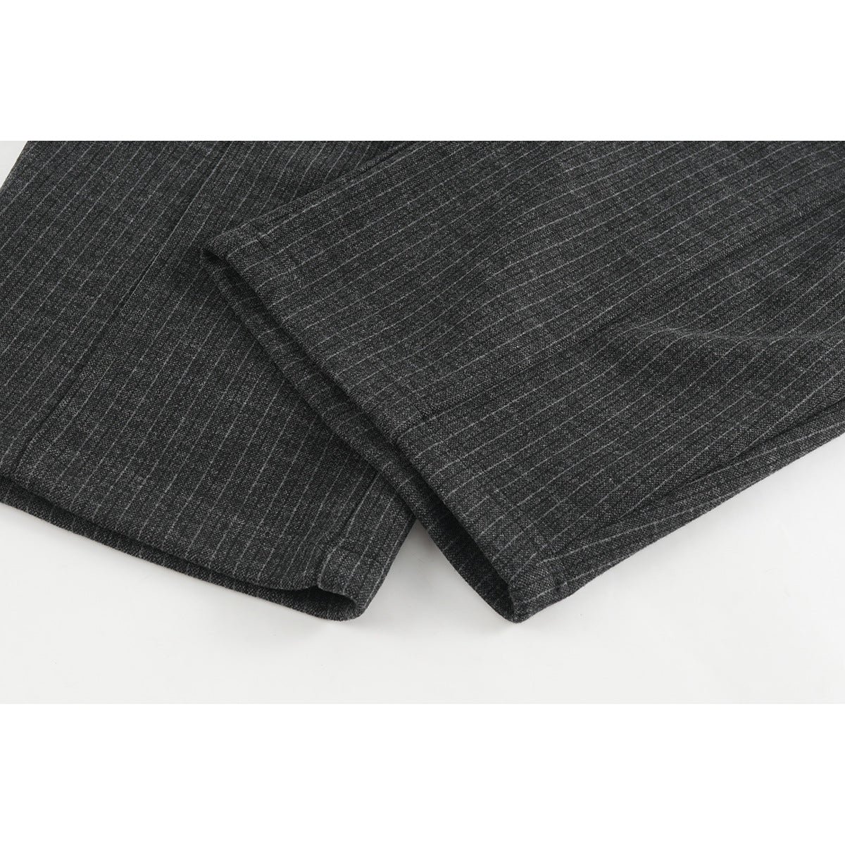 Close-up of charcoal pinstripe trouser legs, showing the fabric pattern and finished hems.