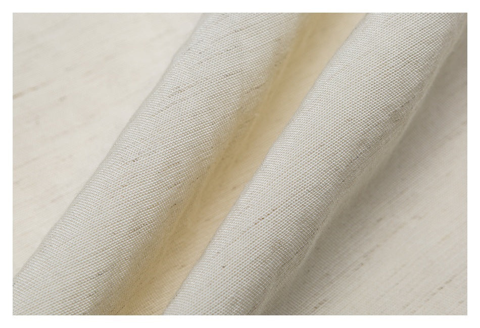 Close-up of cream-colored woven fabric showing its fine textured weave.