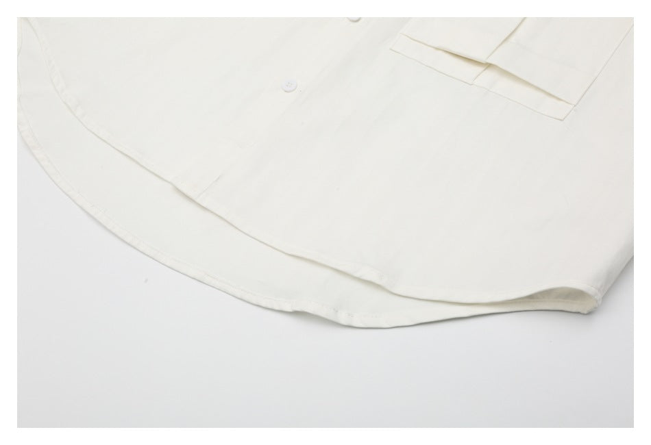 Close-up of the curved hem and lower front of an off-white shirt.