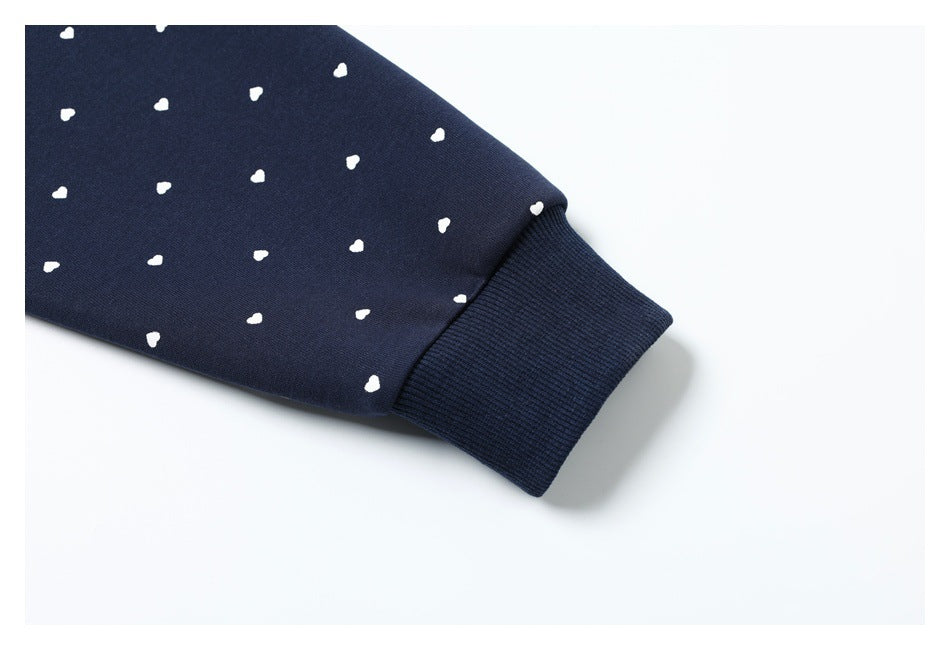 Close-up of the ribbed cuff on a navy hoodie with small white heart prints.