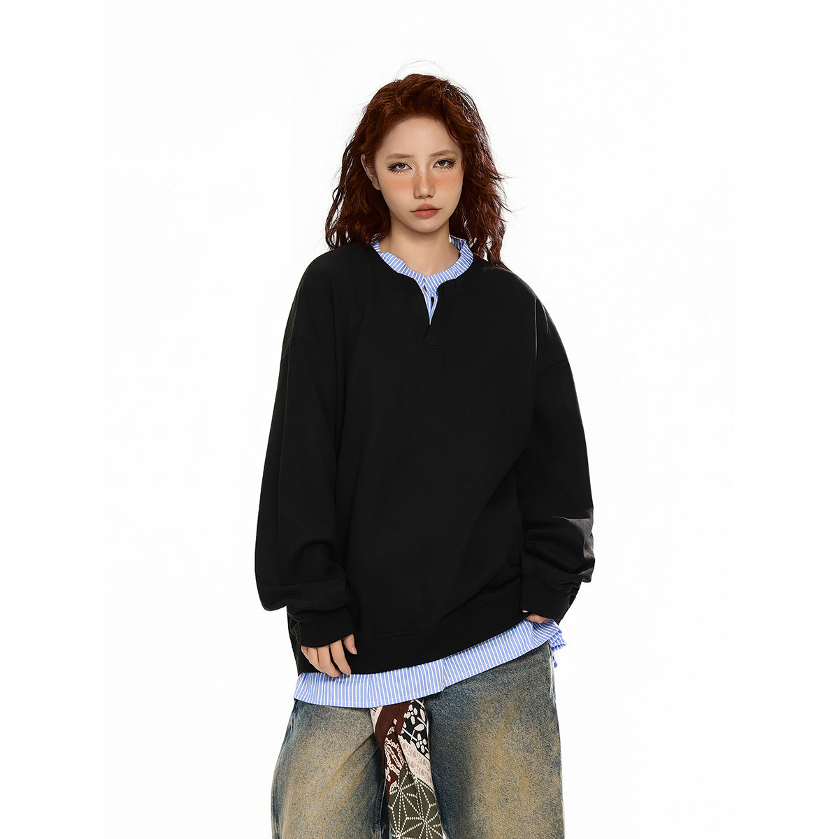 Model wearing an oversized black sweatshirt layered over a blue-and-white striped shirt, with the collar and hem showing.