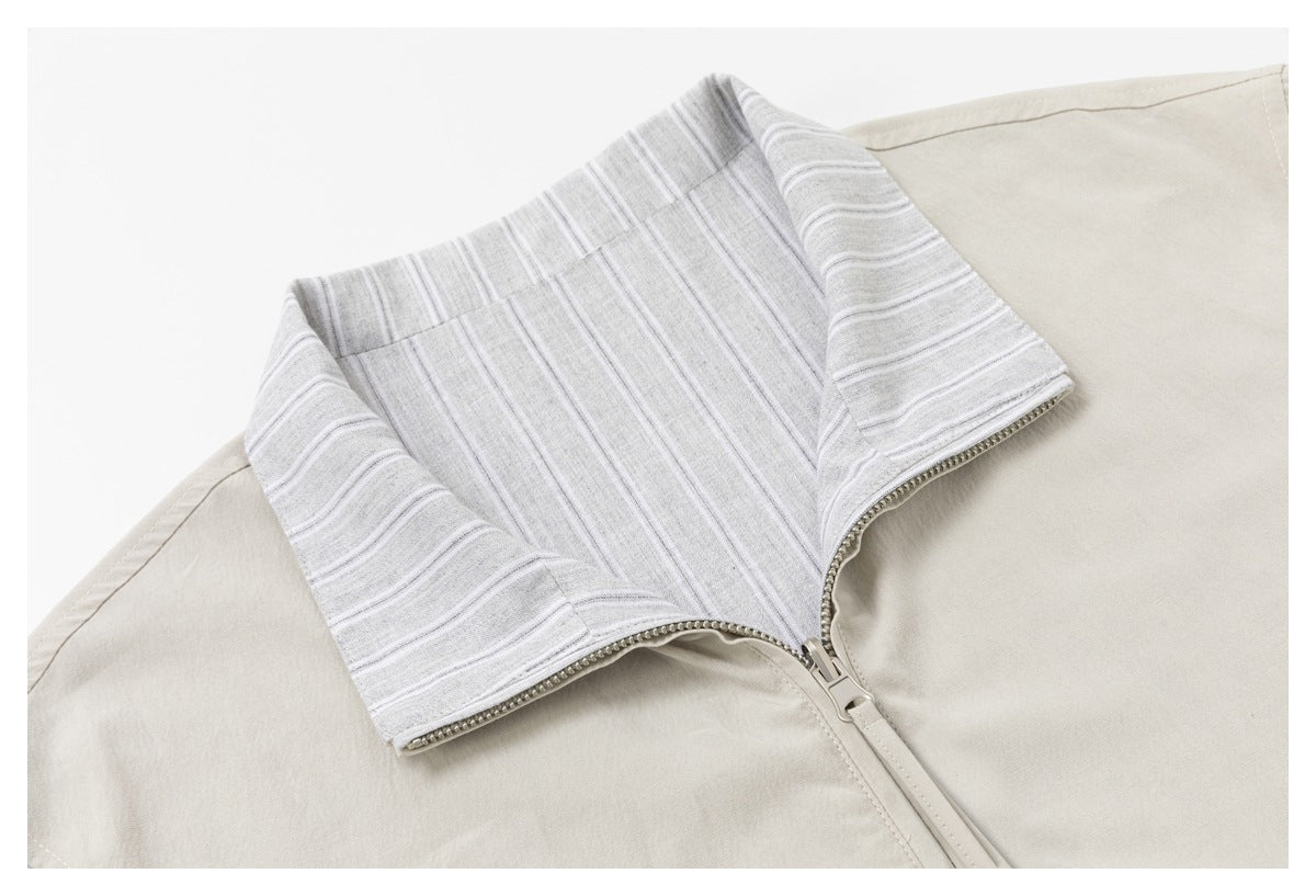 Close-up of a beige jacket with a wide gray-and-white striped collar facing and zipper.