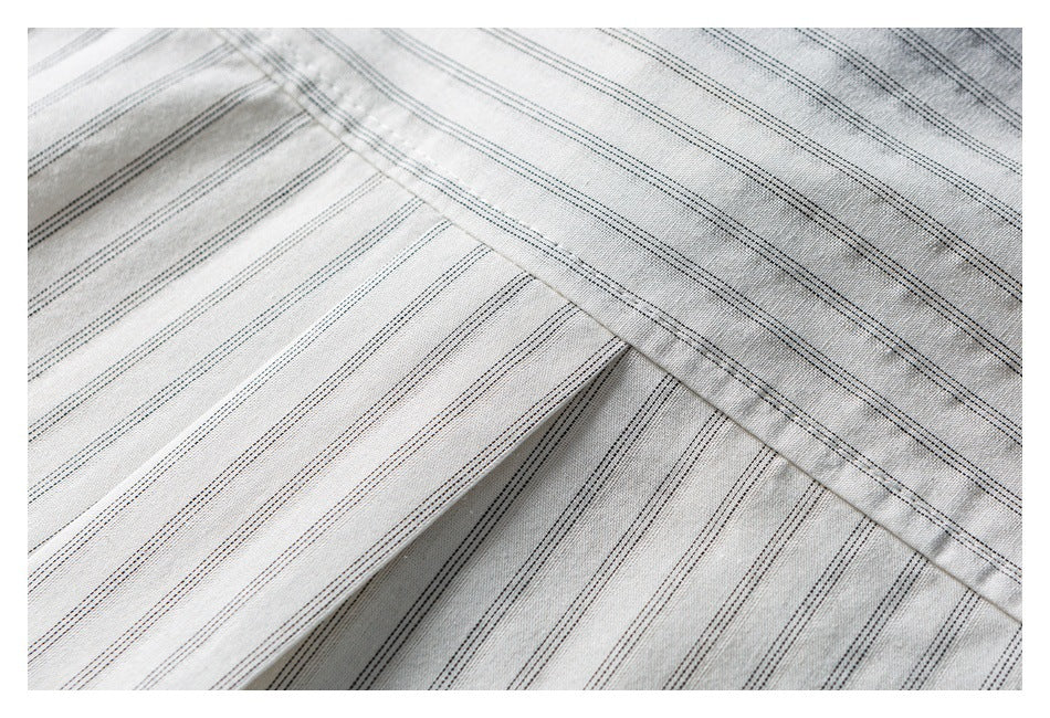 Close-up of light gray pinstriped fabric showing overlapping panels and a diagonal stitched seam.