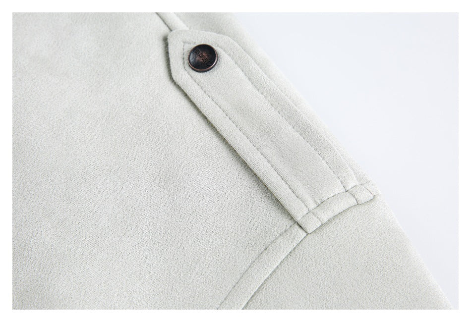 Close-up of an off-white coat shoulder tab with a dark button and stitched seams.