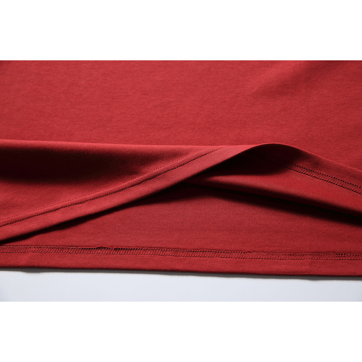Close-up of the red T-shirt's folded hem and stitching.