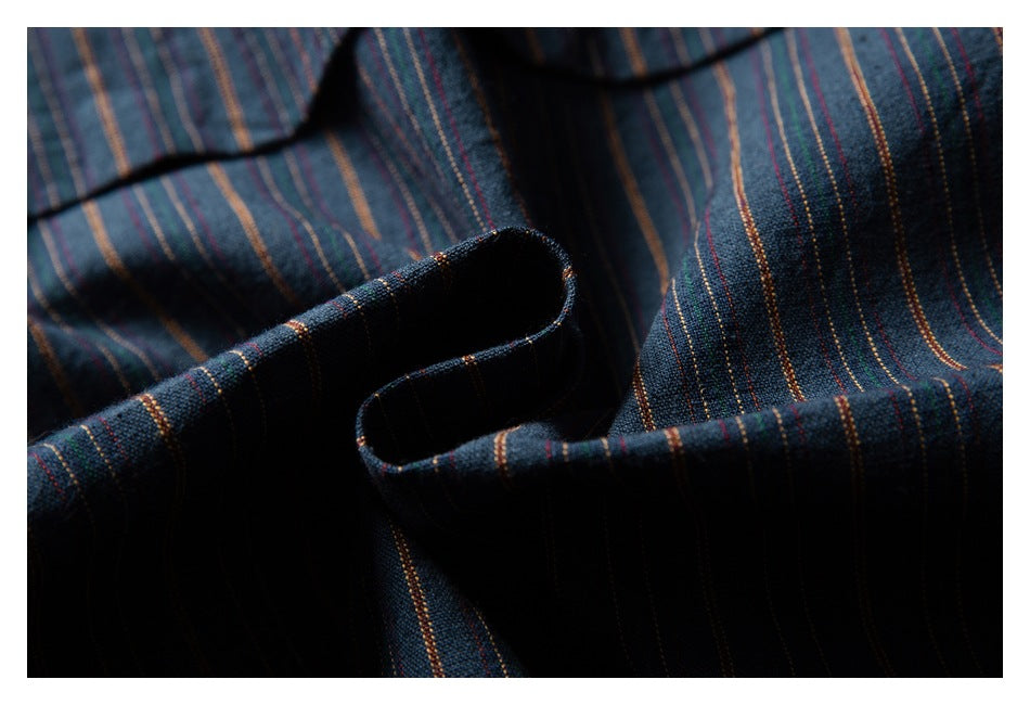 Close-up of dark navy fabric with fine multicolored vertical stripes and soft folds.