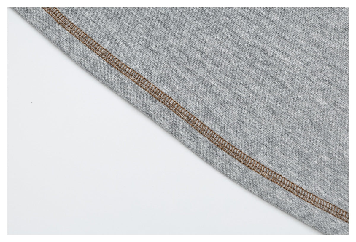 Close-up of brown overlock stitching along the edge of gray heather T-shirt fabric.