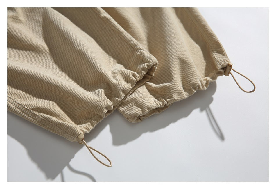 Close-up of beige pants with elasticated cuffs and adjustable loop drawcords.