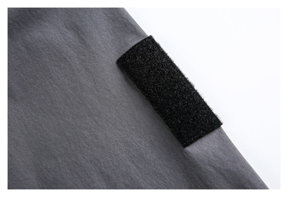 Close-up of a black hook-and-loop tab attached to charcoal-gray garment fabric.