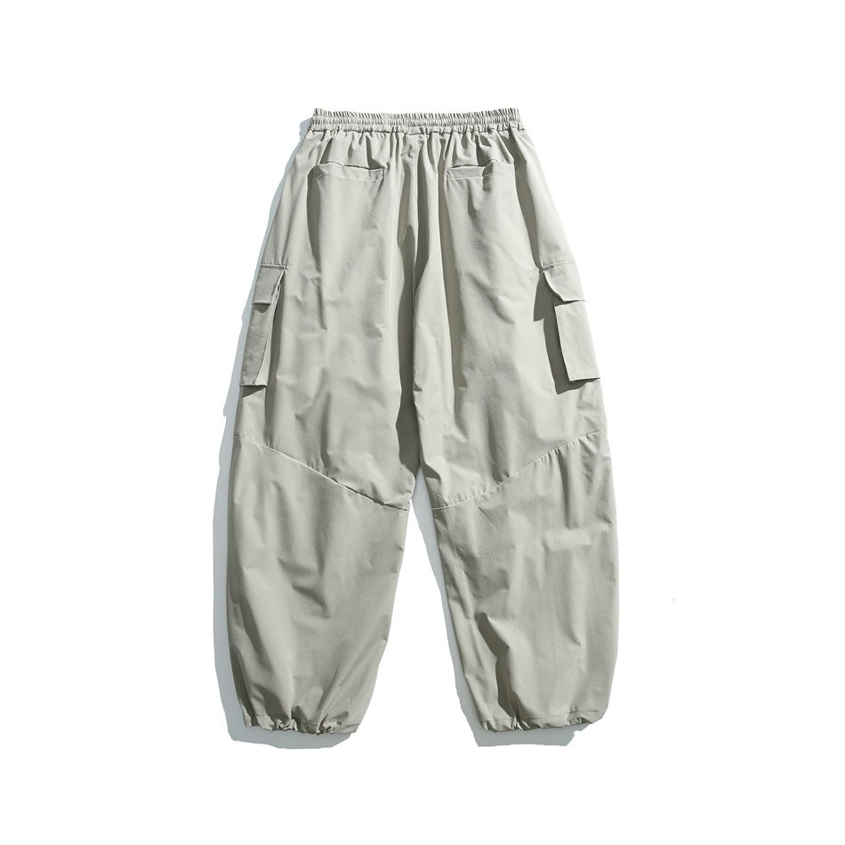 Back view of light gray cargo pants with an elastic waistband, rear pockets, flap side pockets, and gathered cuffs.