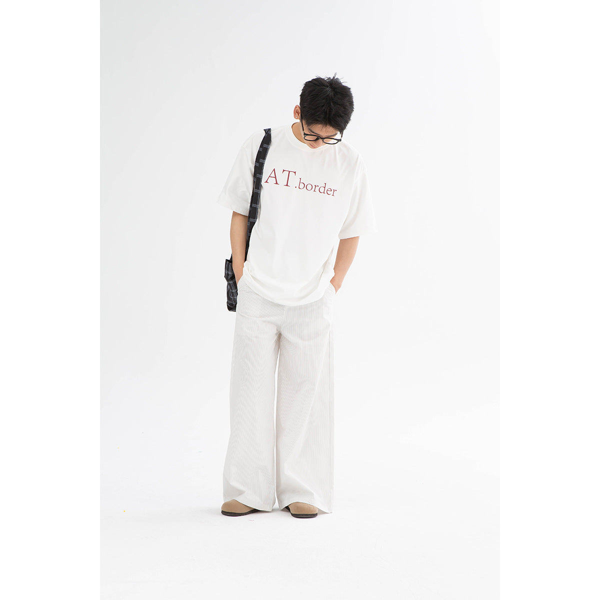 Model wearing a white oversized T-shirt with red lettering and loose white trousers.