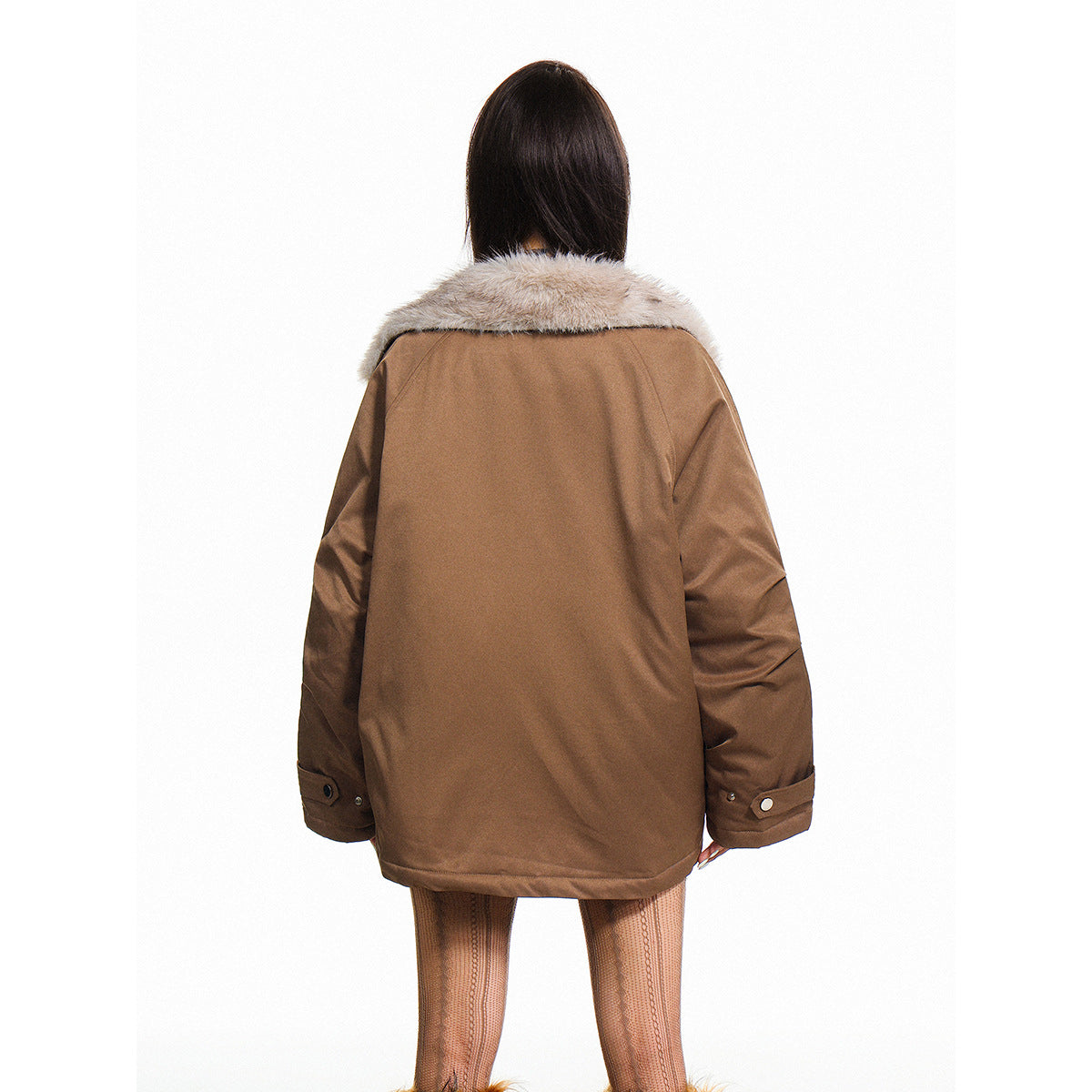 Back view of a model wearing a brown oversized jacket with a pale fur collar and buttoned cuffs.