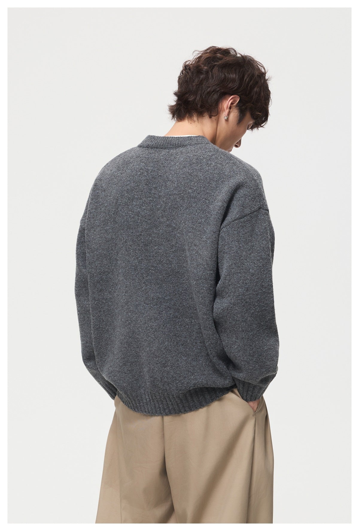 Back view of a model wearing a charcoal gray sweater with a ribbed collar, cuffs, and hem.