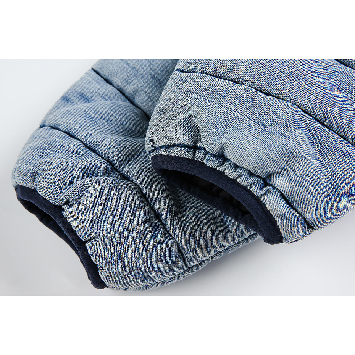 Close-up of padded light blue quilted jacket fabric and a navy-trimmed edge.