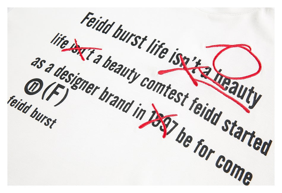Close-up of black English lettering and red embroidered marks on the white T-shirt.