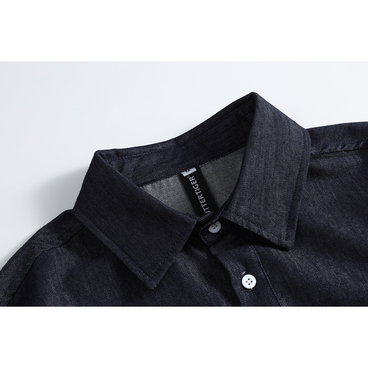 Close-up of a dark indigo shirt collar, placket, white buttons, and inner neck label.