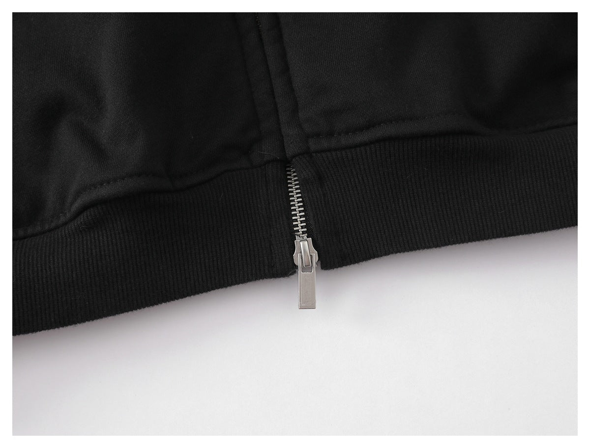 Close-up of a black garment's silver zipper ending at a ribbed hem.