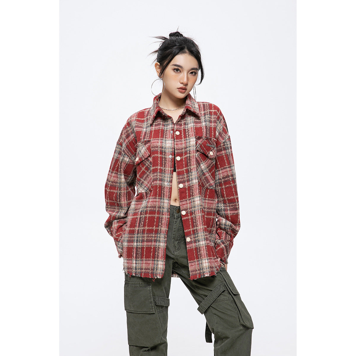 Front view of a model in an oversized red plaid shirt jacket with snap buttons, flap pockets, and a frayed hem.
