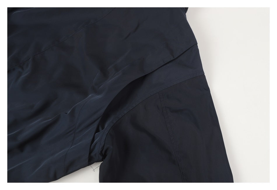 Close-up of a dark navy garment showing overlapping panels and curved seams.